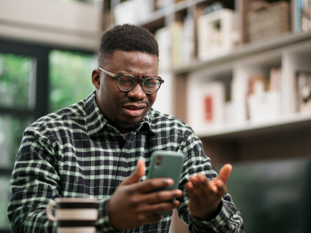 An upset man is staring at his cell phone (Getty/Stock Photo).
