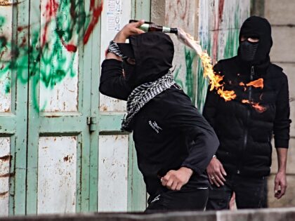 A Palestinian youth hurls a Molotov cocktail against Israeli troops during confrontations