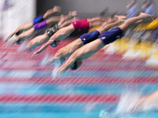 Swimmers leaps from the starting blocks to compete in the Men's 50m Freestyle heats on day