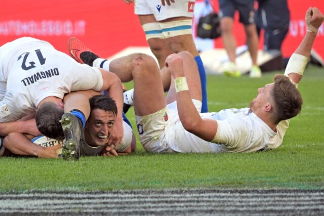 Alex Mitchell, buried under team-mate Fraser Dingwall, reacts after scoring England's seco