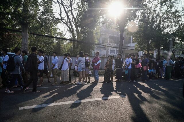 People stand in line to get visas at the Thai embassy in Yangon after Myanmar's military g