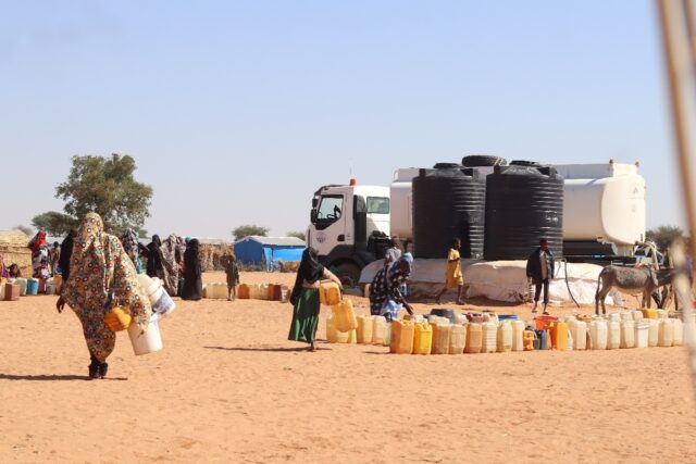 Refugees fleeing the conflict in Sudan queue to collect drinking water from the Doctors Wi