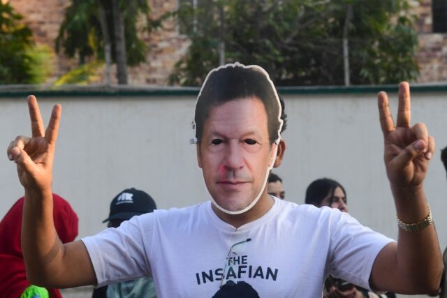 A man wearing a mask of jailed former Pakistan prime minister Imran Khan protests against