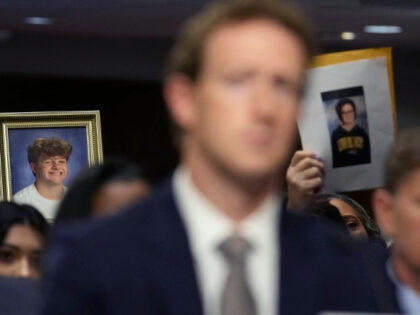 People in the audience hold up photos of their loved ones behind Meta CEO Mark Zuckerberg