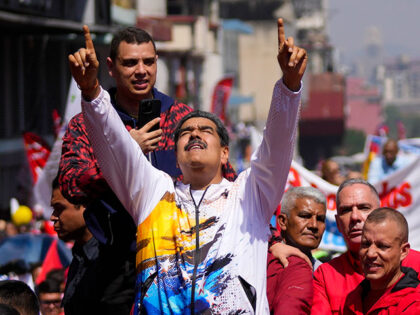 Venezuelan President Nicolas Maduro points to the sky as he is driven to the National Elec