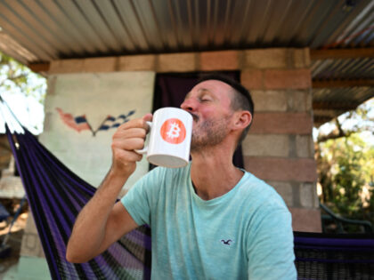US bitcoiner Corbin Keegan drinks from a mug with the Bitcoin logo during an interview wit
