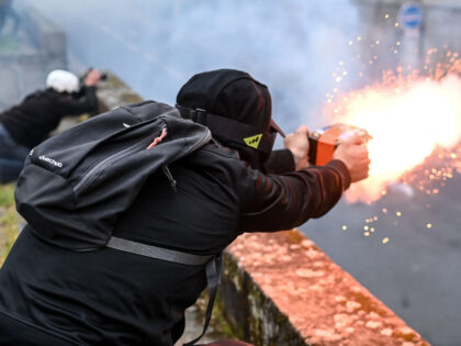 TOPSHOT - A protester uses fireworks towards French police officers during an action day,