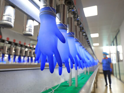 A worker checks the quality of medical gloves at a factory on June 28, 2021 in Tangshan, H