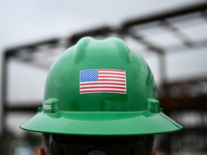 A US flag is displayed on a construction worker's safety helmet during a topping out