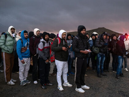 Asylum seekers wait in line to be processed by the Border Patrol at a makeshift camp near