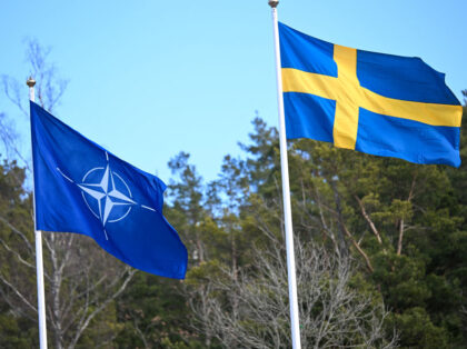 The NATO flag is raised next to a flag of Sweden (R) at a ceremony at the Musko navy base