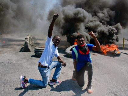 Protesters react while tires burn in the street during a demonstration following the resig