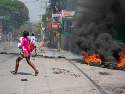 A woman carrying a child runs from the area after gunshots were heard in Port-au-Prince, H