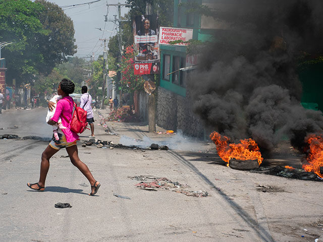 A woman carrying a child runs from the area after gunshots were heard in Port-au-Prince, H