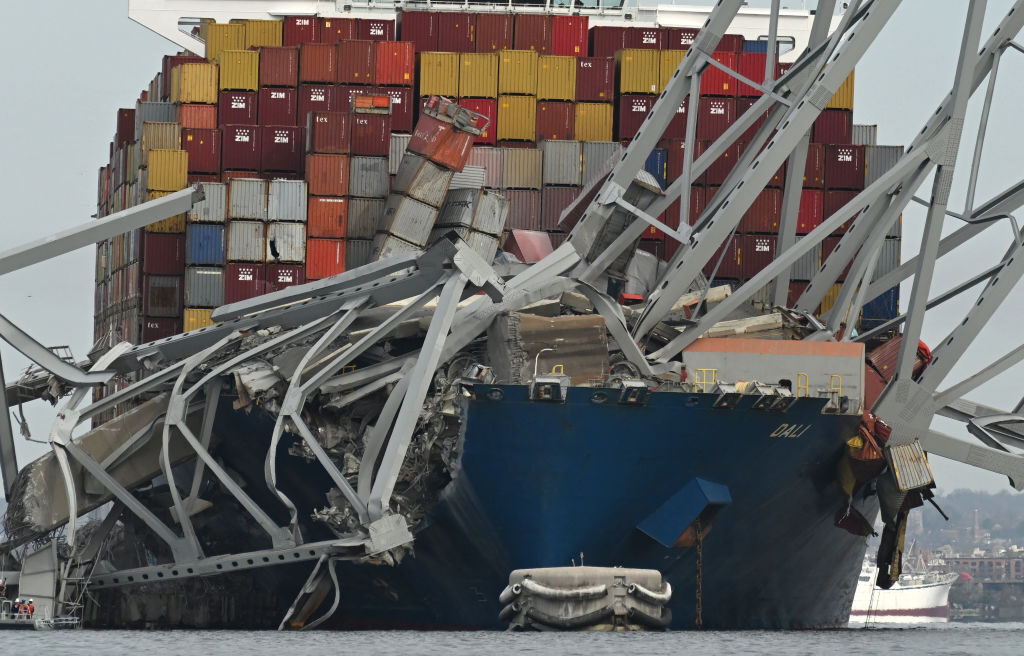 TOPSHOT - The steel frame of the Francis Scott Key Bridge sits on top of the container ship Dali after the bridge collapsed, Baltimore, Maryland, on March 26, 2024. The bridge collapsed early March 26 after being struck by the Singapore-flagged Dali, sending multiple vehicles and people plunging into the frigid harbor below. There was no immediate confirmation of the cause of the disaster, but Baltimore's Police Commissioner Richard Worley said there was "no indication" of terrorism. (Photo by ROBERTO SCHMIDT / AFP) (Photo by ROBERTO SCHMIDT/AFP via Getty Images)