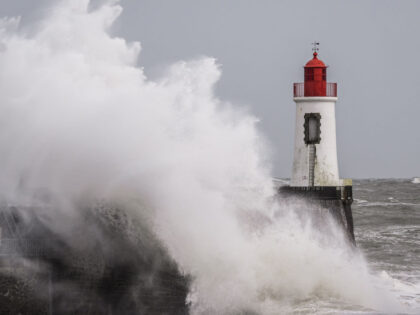 Waves crash against the lighthouse at the entrance to the harbour during Storm Nelson, in