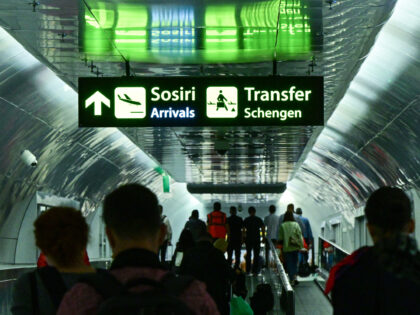 Travelers walk next to newly installed signs pointing to Schengen transfer flights areas,