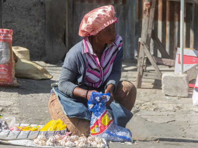 PORT-AU-PRINCE, HAITI - MARCH 21: A merchant sits with a basket of garlic to sell in the p