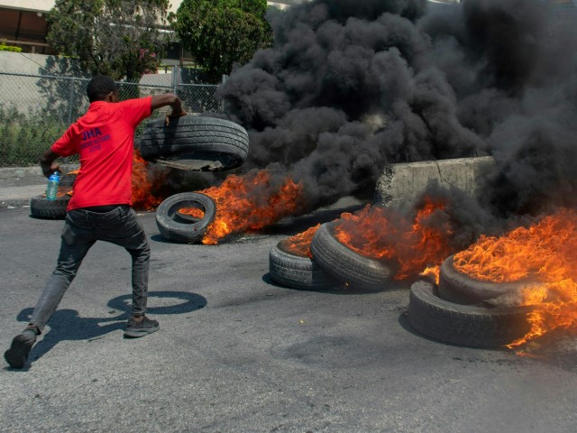 A protester burns tires during a demonstration following the resignation of its Prime Minister Ariel Henry, in Port-au-Prince, Haiti, on March 12, 2024. A political transition deal in Haiti marks a key step forward for the violence-ravaged country but far more needs to be done, with some experts warning the situation could deteriorate further. (CLARENS SIFFROY/AFP via Getty)