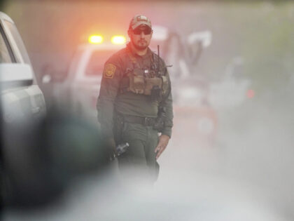 A Customs and Border Patrol agent walks near the site where a helicopter flying over the U
