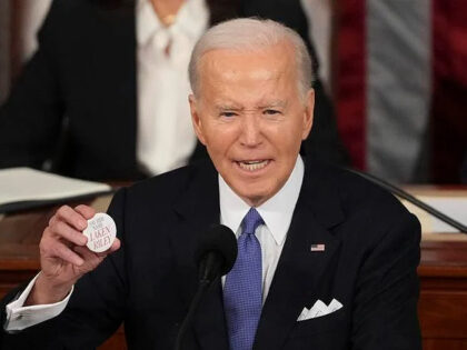 President Joe Biden holds up a Laken Riley button as he delivers the State of the Union ad