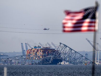 An American flag flies on a moored boat as the container ship Dali rests against wreckage