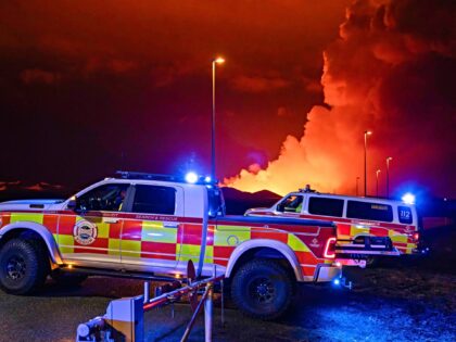 Emergency vehicles are seen as molten lava flows out from a fissure on the Reykjanes penin
