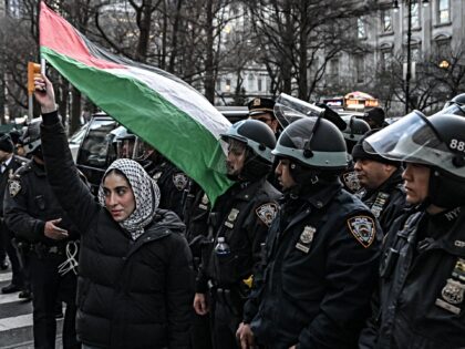 NEW YORK, UNITED STATES - MARCH 19: A woman holds a Palestinian flag in front of officers