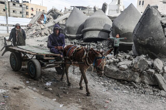 A donkey-pulled cart passes the rubble of Al-Faruq Mosque, destroyed during Israeli bombar