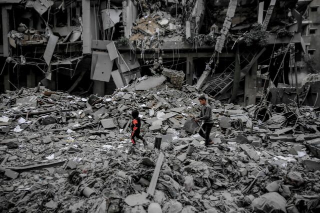 Palestinians walk amid the rubble of houses destroyed by Israeli bombardment in Gaza City