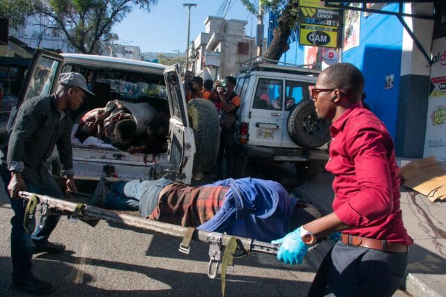 Paramedics carry the body of a person killed by gang members in Petionville, Port-au-Princ