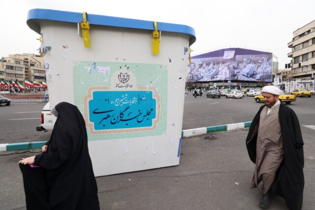 A Shiite Muslim cleric and a woman in front of an installation in the form of a giant ball