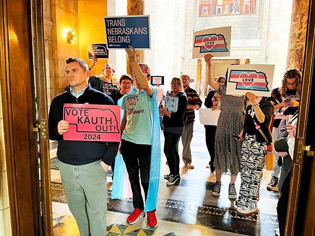 Protesters hold signs outside the doors of the legislative chamber in the Nebraska State C