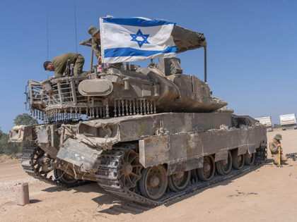 An Israeli soldier attaches an Israeli flag on top of an armoured personnel carriers (APC)