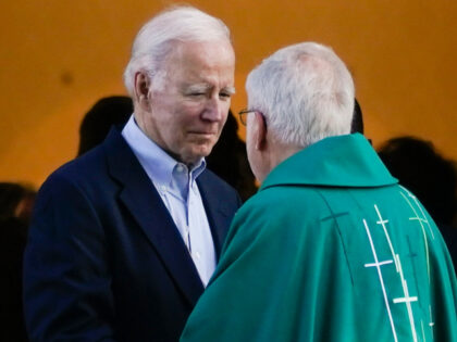President Joe Biden talks to a priest as he leaves …