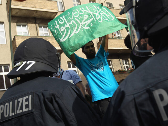 BERLIN, GERMANY - AUGUST 18: Riot police watch as a protester waves a flag with Arabic wri