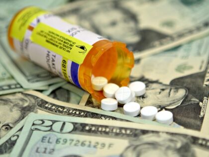Prescription pills spilling out of the bottle on a twenty dollar bills background.