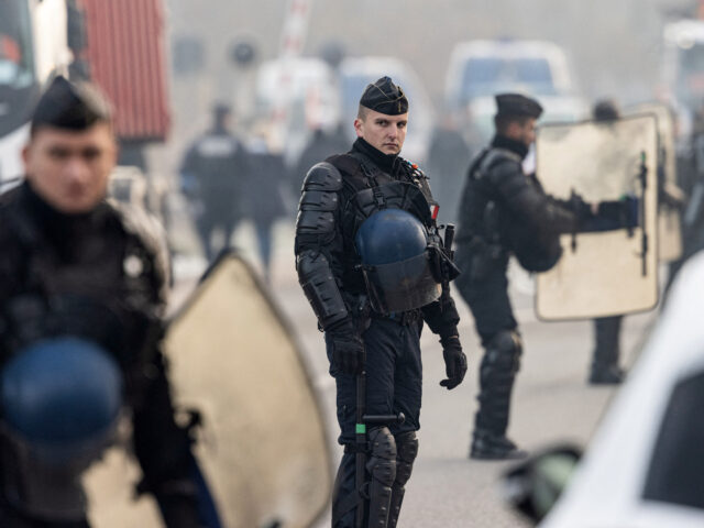 French Gendarme officers look on as migrants are evacuated from a makeshift camp to recept