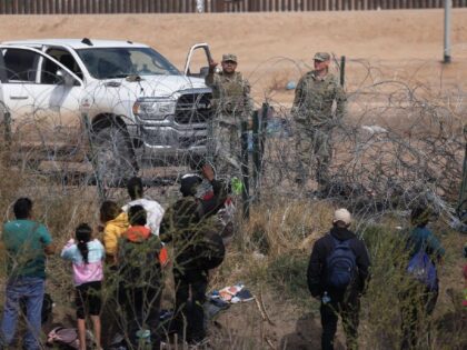 Texas National Guard agents prevent migrants from Venezuela from crossing a barbed wire fe