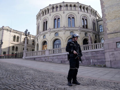 An armed Police officer patrols the area outside the Norwegian Parliament building On Apri