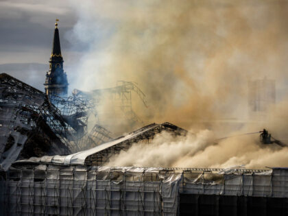 A firefighter tries to extinguish the flames as plumes of smoke billow from the historic B