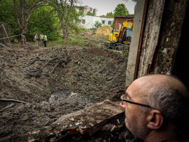 KHARKIV, UKRAINE APRIL 27: A kitchen worker looks at a sinkhole caused by a Russian missil