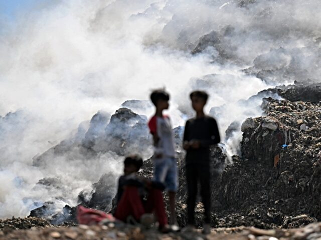 Boys are silhouetted against the smoke billowing from a fire that broke out at the Ghazipu