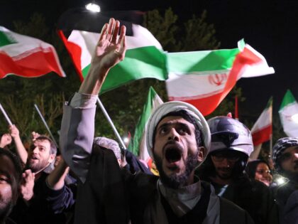 Demonstrators wave Iran's flag and Palestinian flags as they gather in front of the B