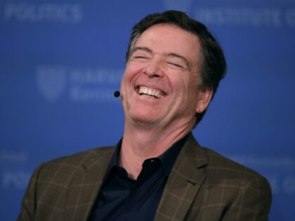 Former Director of the Federal Bureau of Investigation James Comey laughs while addressing