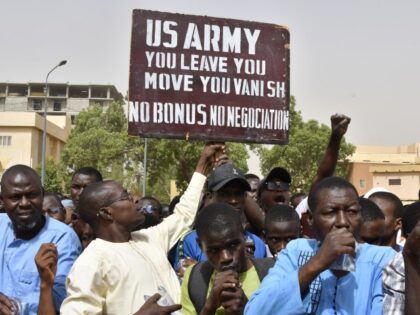 Protesters react as a man holds up a sign demanding that soldiers from the United States A