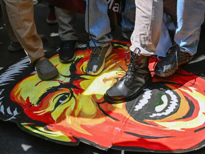 TOPSHOT - Protesters step on a caricature of China's President Xi Jinping as they take par