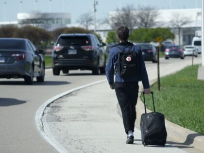 A passenger walks on the highway as he carries his luggage to at O'Hare International