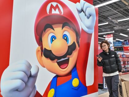 Woman walks in front of a mario poster from Nintedo
