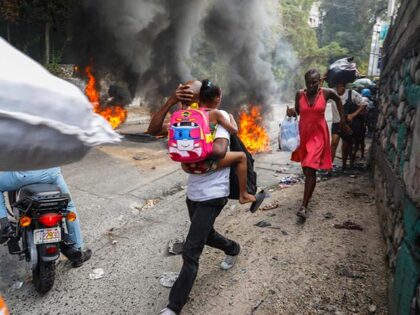 People walk past burning tires during a protest against Haitian Prime Minister Ariel Henry